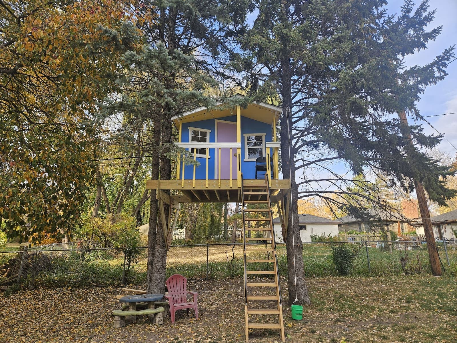Blue and yellow four-season treehouse built twelve feet above the ground